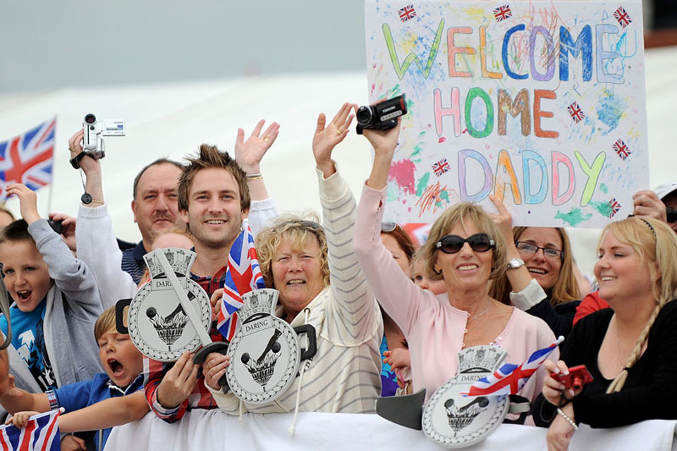 Families and friends wave to their loved ones on board HMS Daring