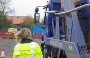 An Environment Agency Officer by the side of a waste carrier lorry.