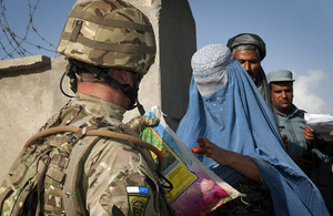 A British soldier hands a bag of rice to an Afghan woman at the Khuja Rawash Secondary School in Kabul