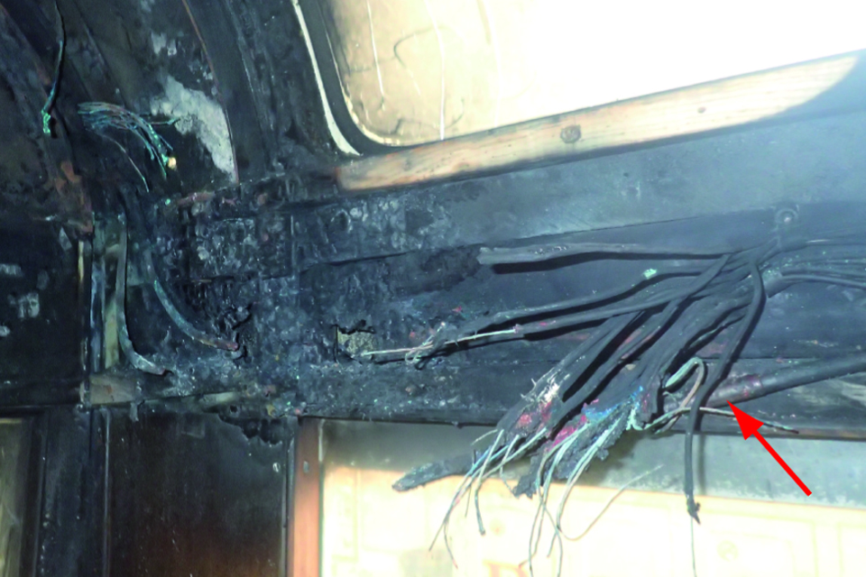 Fire damaged cabling within the roof space of tram 272. The previous cable repair is indicated by a large red arrow on the right hand side.
