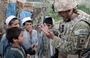 A British soldier chatting to Afghan children during a joint patrol with the Afghan National Police and Afghan National Civil Order Police in the Bolan area