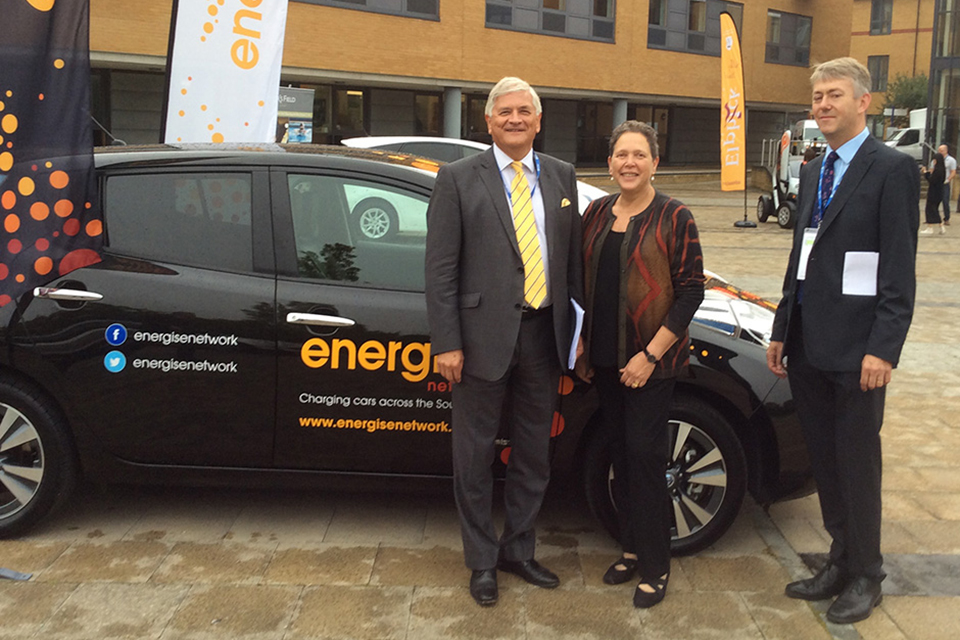 Baroness Kramer with attendees and green car.