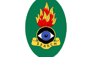 The oval-shaped badge is emblazoned with the word 'SEARCH', with a design of an eye and flame above it, to represent the nature of the Search Teams' work