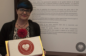 Baroness Neville-Rolfe holding a Women in Finance Charter 1 year anniversary cake