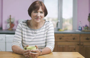 A healthy woman holding a cup in a kitchen.