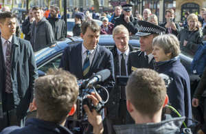 Prime Minister Theresa May visiting Salisbury, pictured with police officers and a crowd of people.