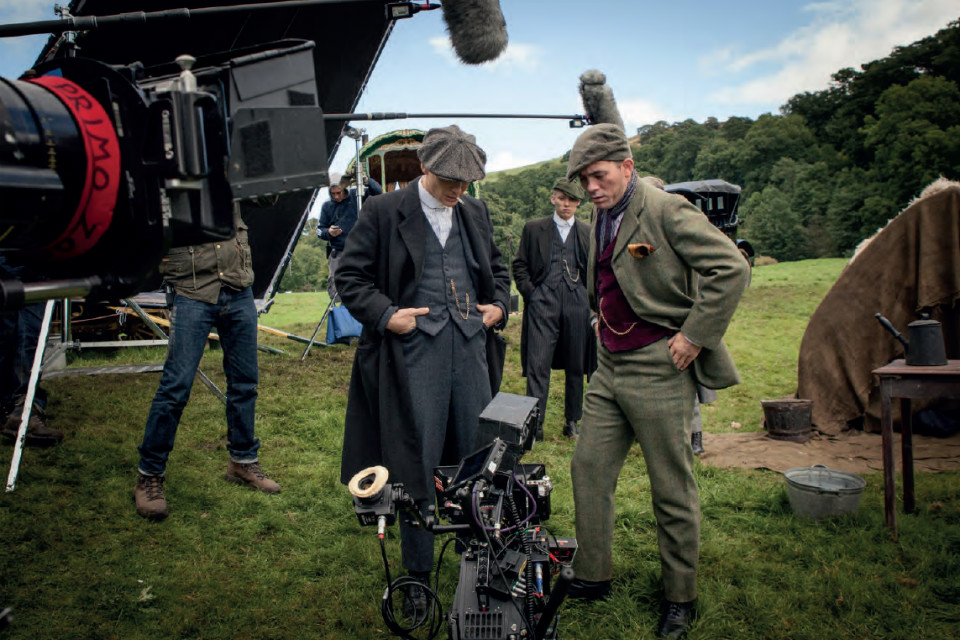 Actors and camera crew from 'Peaky Blinders' filming in a field.