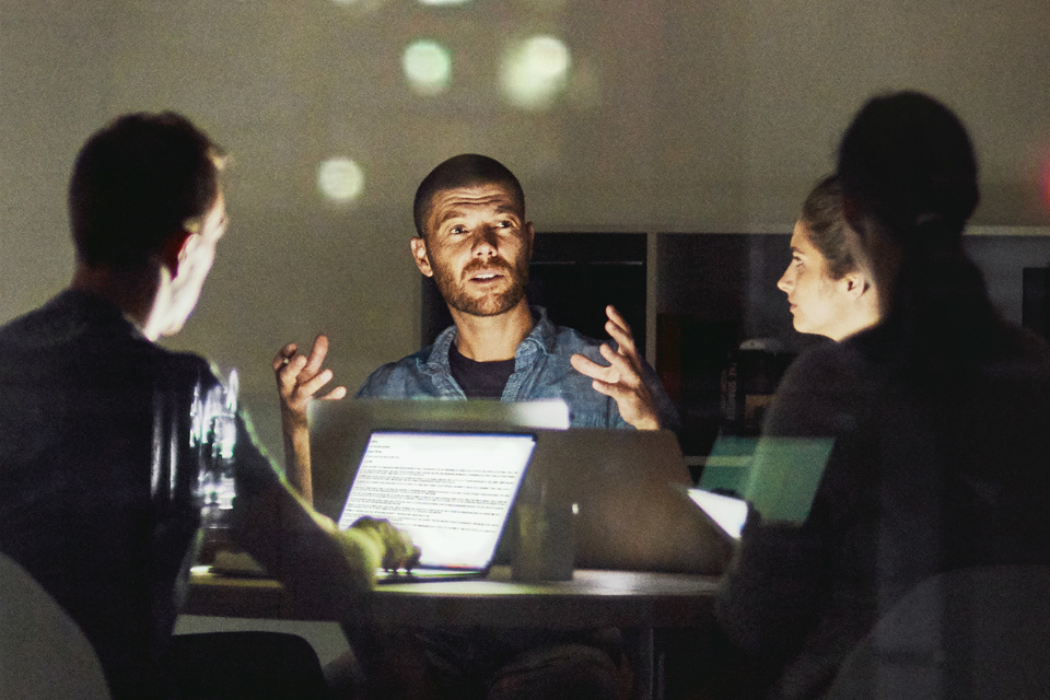 A business meeting at night illuminated by a laptop (credit: Cecilie_Arcurs / iStock)