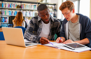 2 young students in library discussing university options.