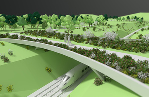 Animation of a train going under a green bridge lined with shrubs with a family walking across it.