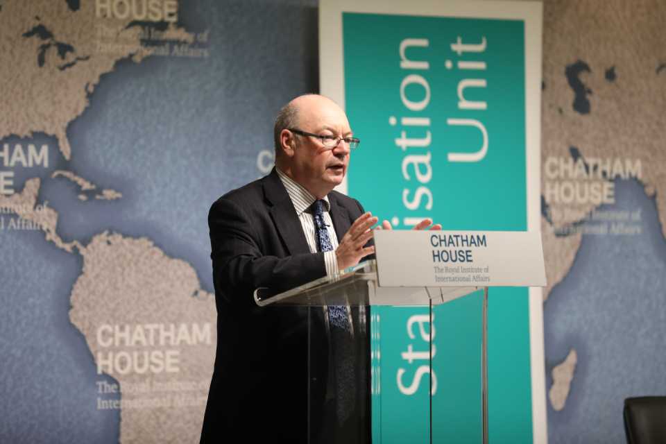 Minister for International Development Alastair Burt stands at a lectern with a map of the world behind him.