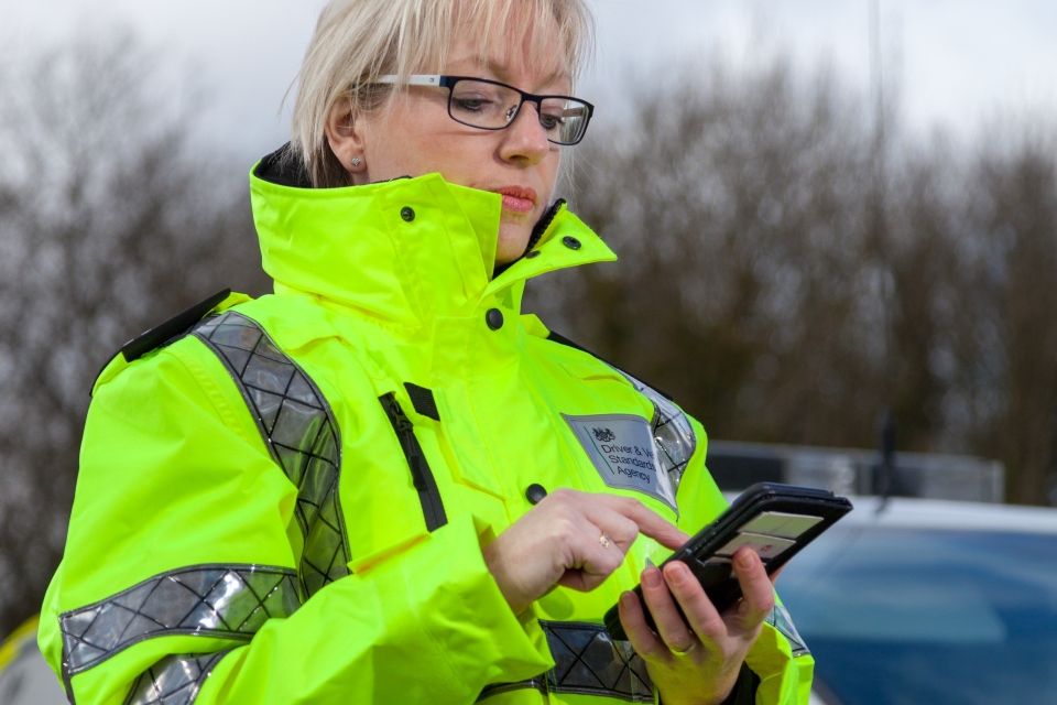 Image of a traffic examiner using a smartphone at the side of a car