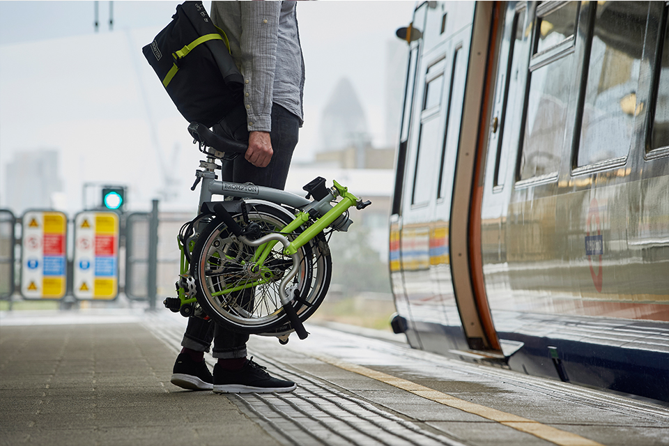 Man holding folded Brompton bike before getting on underground train