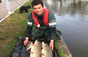 Environment Agency officer with fish at water's edge