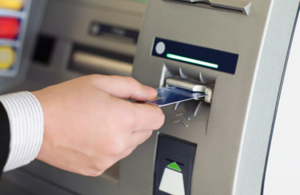 A man putting a bank card into an ATM machine.