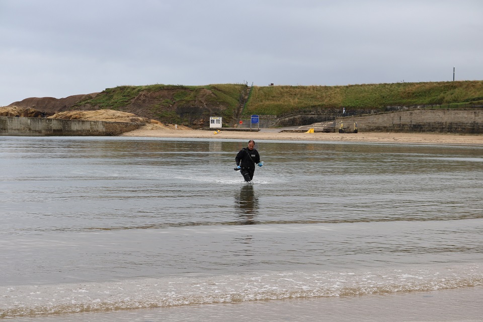 The image shows the Environment Agency's Mick Donkin collecting samples at Cullercoats