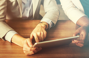 Image of two people holding a tablet device