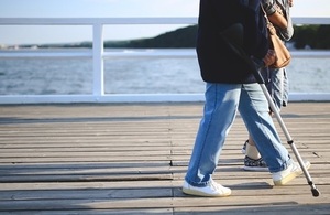 Woman using crutches walking by on pier.