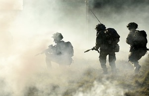 Three armed troops within smoke, two soldiers walking and one soldier crouching down