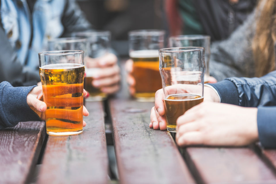 A picture of people sat around a table outside holding beer glasses