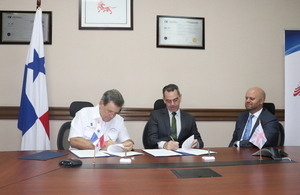 José Gómez Núñez, Director General of the National Customs Authority and the Regional Manager of the British Border Force, Michael Kane sign an agreement with British Ambassador Damion Potter as a witness.