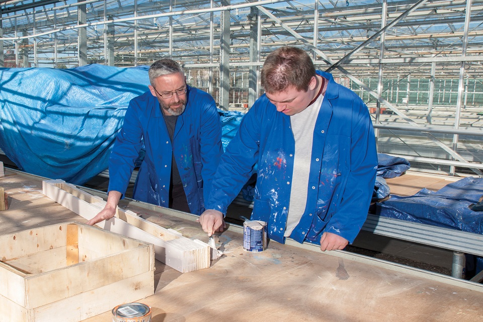 Carpentry student and teacher together in front of workbench