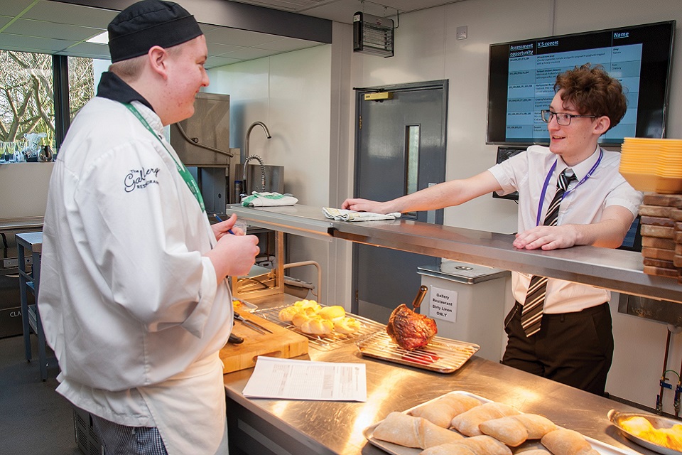 Catering student talking to another student at food bar