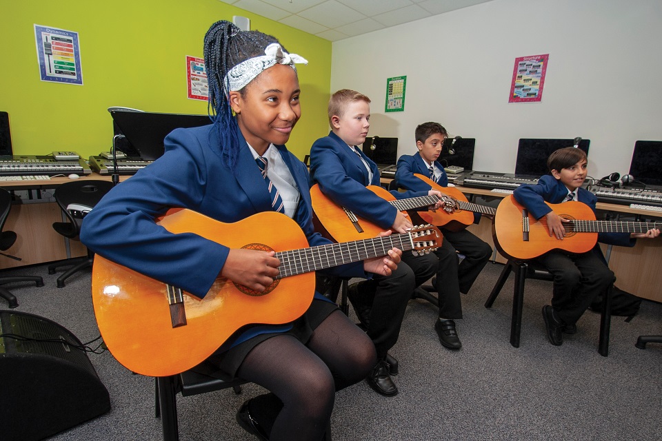 Four secondary school pupils sitting down playing guitars