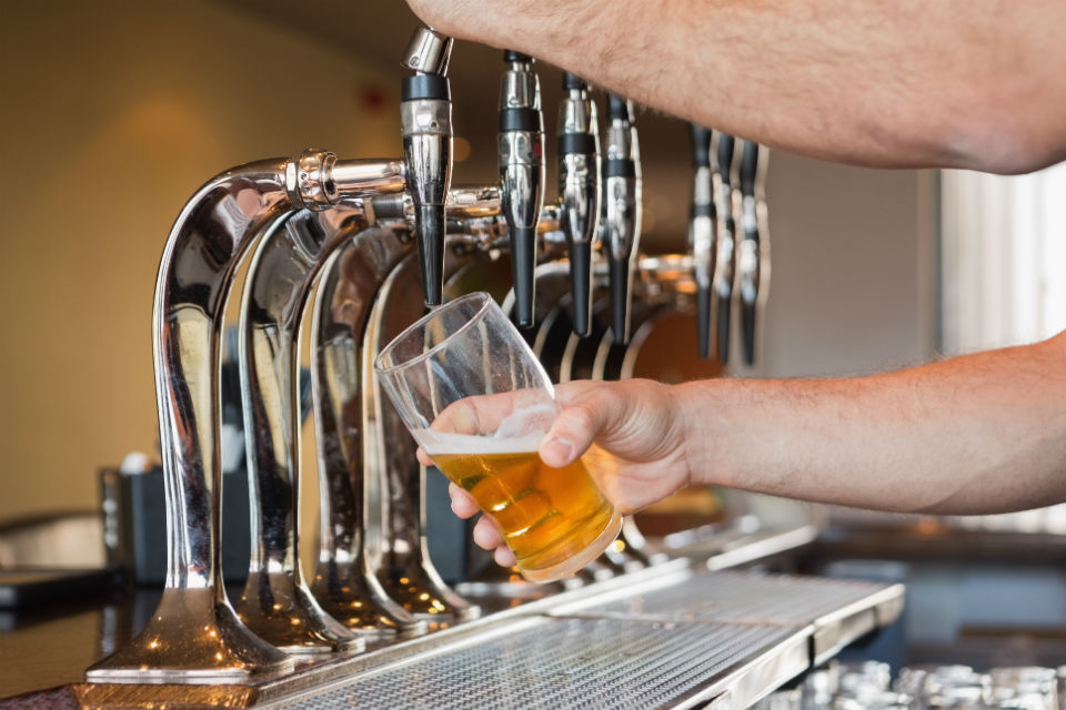 A picture of a person pouring a pint at a bar.