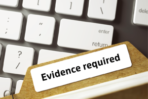 Laptop keyboard with file marked 'Evidence required' lying across it