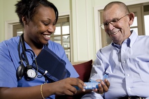 A nurse shows a male patient some pills.