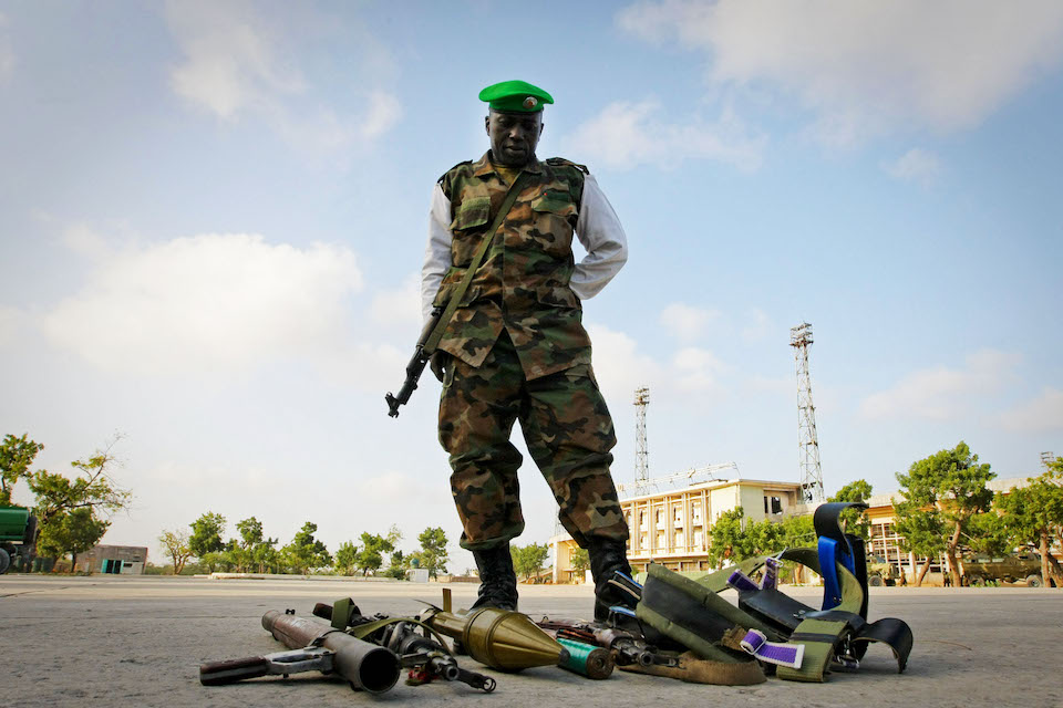 A soldier stands over the weapons seized from four suspected members of Al Shabaab, the Islamic insurgent group, in Mogadishu, Somalia. (UN Photo)