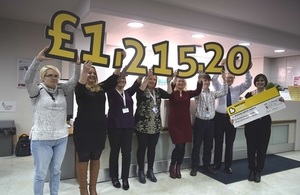 Image of the fundraisers holding cards which display the total fundraising amount.