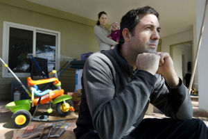 photo of family in a room - father in foreground, mother and baby in background