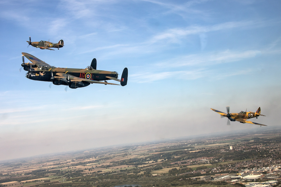 Historic aircraft fly over the countryside.