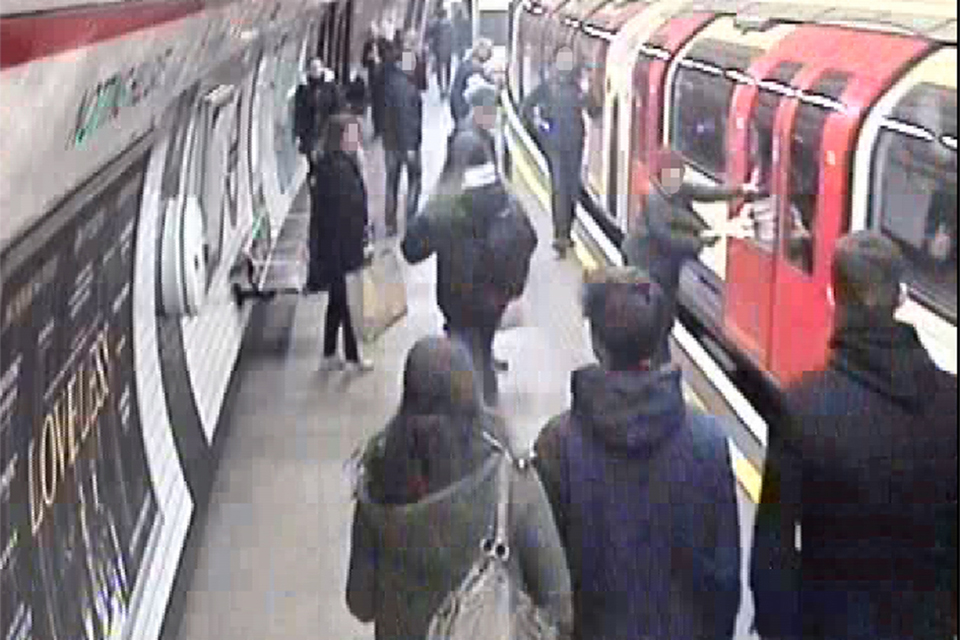 Platform CCTV of passengers at Notting Hill Gate underground station. The departing train is on the right of the image with a passenger and their clothing trapped in the doors.