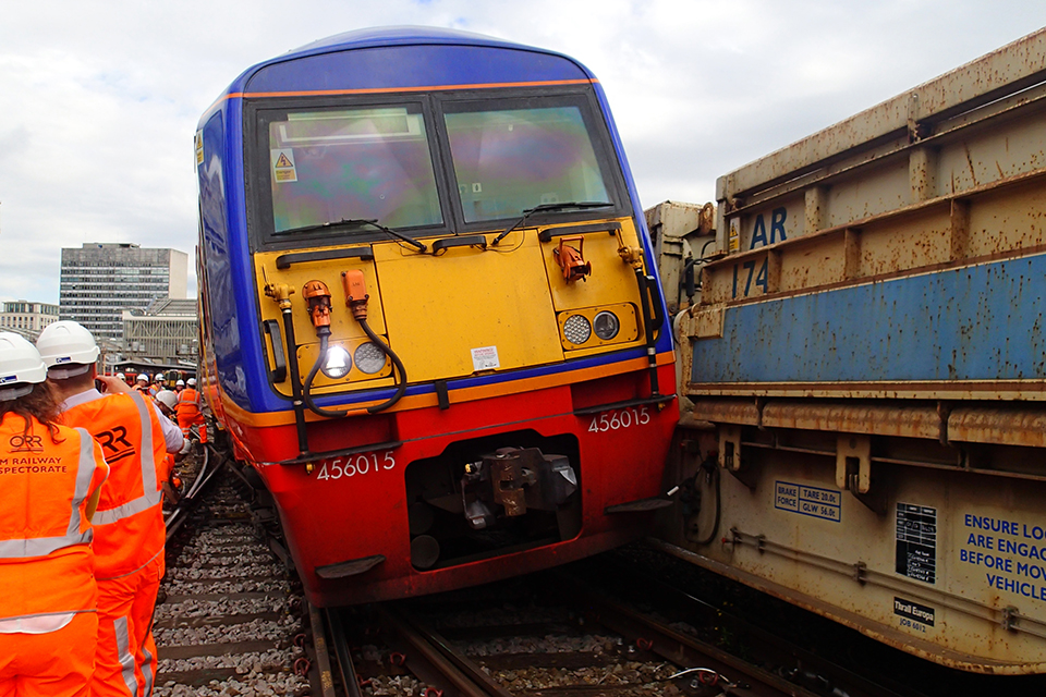 The derailed train at Waterloo in blue, yellow and red livery after striking the barrier vehicles. Railway staff in high visibility clothing are in attendance