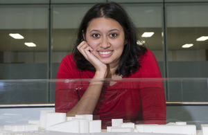 Woman in red top posing in front of 3d model.
