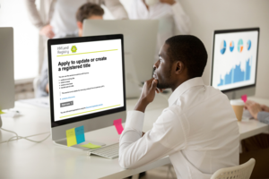 A man using the 'apply to create to update a registered title' service on an Apple Mac computer.