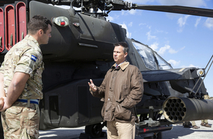 Minister for the Armed Forces Mark Lancaster speaks to a British Army soldier in front of a helicopter