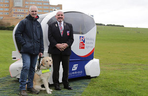 Blind veterans Dave Woollett and Alan Walker and guide dog Jasper with a driverless car.