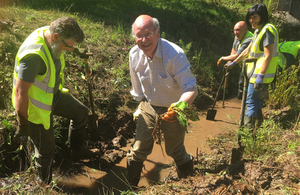 Lord Gardiner with volunteers digging out American skunk cabbage from a drainage channel in Kent