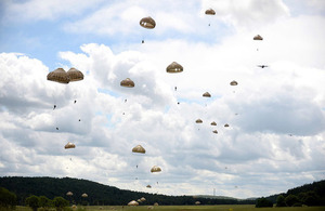 Paratroopers parachute through the sky