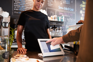 Person paying at a cafe using a tablet device.
