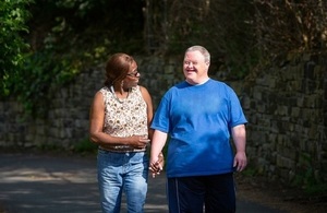 Carer walking with a man with Down's syndrome walking down the street