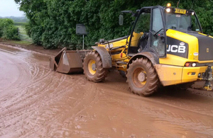A digger removing mud washed on to the road