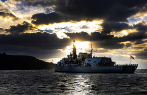 HMS Monmouth sailing with the backdrop of a sunrise