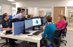 Photograph of people sitting around desks