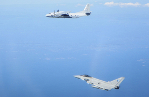 An RAF Typhoon jet flies alongside a Russian fighter jet against a bright blue sky