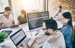People sitting round a desk working on computers